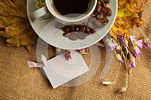 The cup of coffee with maple leaves and everlasting flowers