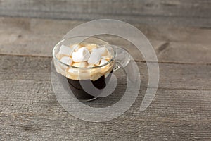 Cup of coffee with marshmallows on a wooden table. Street food