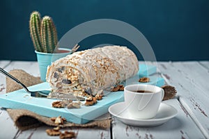 A cup of coffee meringue roll on a white vintage wooden kitchen table with burlap napkin