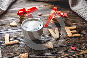 Cup of coffee and a message from a sweet cookie in the form of the word love. Romantic Valentine`s day gift
