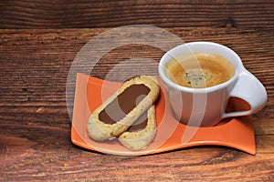 Cup of coffee in the middle of coffee beans with biscuits and tablecloth. Grained product. Hot drink. Close up. Harvesting. Natura