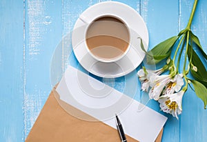 Cup of coffee with milk, blank paper in the envelope, pen and al