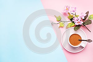 A Cup of coffee with milk and branch with flowers and leaves.on a pink pastel background with copy space. Flat lay