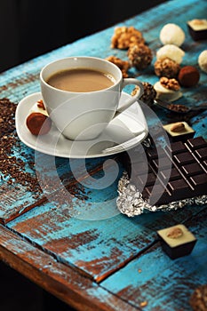 Cup of coffee with milk, chocolate bar and variety candies