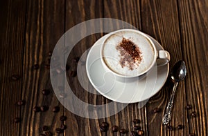 A Cup of coffee with milk and coffee beans on a dark wooden background. selective focus
