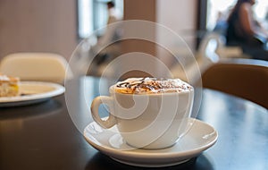 Cup of coffee with milk foam and cake in cafe