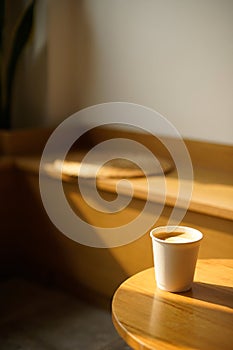 Cup of coffee with milk put on a chair in sunlight shade cafe with cozy room