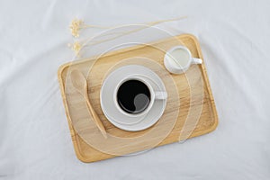 A cup of coffee and milk on wooden plate
