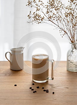 A cup of coffee with milk on a wooden table with coffee beans against the background