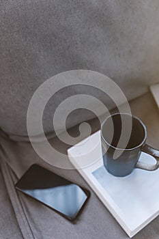 Cup of coffee with mobile phone on sofa in living room