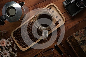 Cup of coffee and moka pot on wooden table.