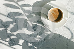 Cup of coffee in the morning light, sunlight shadow, morning breakfast concept, top view, copy space