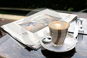 Cup of coffee with news paper on table