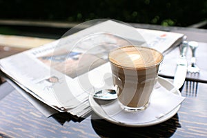 Cup of coffee with news paper on table