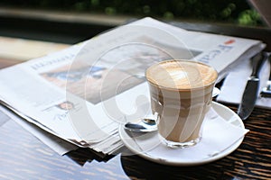 Cup of coffee with news paper on table