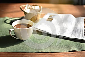 Cup of coffee and newspaper on the table ,shop background,morning,defocus