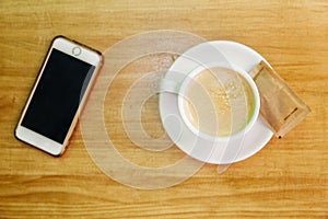 Cup of coffee next to a mobile phone