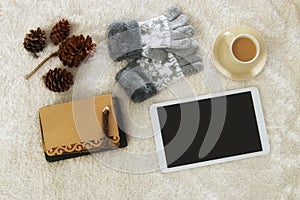 Cup of coffee next to tablet device with empty screen over cozy and warm fur carpet. Top view.