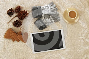 Cup of coffee next to tablet device with empty screen over cozy and warm fur carpet. Top view.