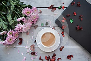 A Cup of coffee,note book , cracker, cookie, biscuit, lupins flowers on a wooden table.