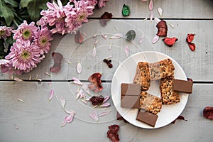 A Cup of coffee,note book , cracker, cookie, biscuit, lupins flowers on a wooden table.