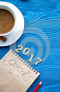 Cup of coffee and notebook with goals for new year