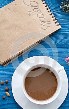 Cup of coffee and notebook with goals for new year