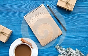 Cup of coffee and notebook with goals for new year