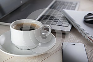 Cup of coffee and notebook, laptop, computer mouse, phone on a t