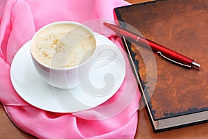 Cup of coffee with notebook and pen