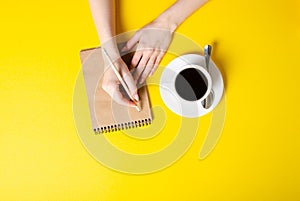 Cup of coffee, notepad, pencil, female hands