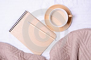 Cup of coffee notepad pencil on a white brown bed