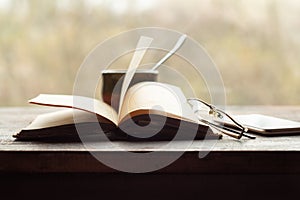 Cup of coffee, old book glasses and phone on the windowsill