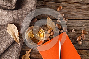 Cup of coffee with an old book and oak leaves. On wooden background.