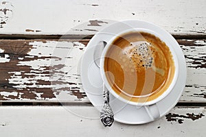 Cup of coffee on the old wooden table with small spoon