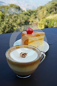 A cup of coffee with orange cake