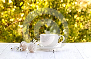 Cup of coffee outdoor with coconut candy balls sunshine on a white wooden board and boxes