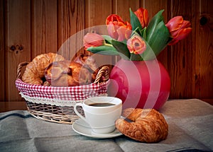 Cup of coffee, pastry and tulip flowers. Selective focus.