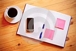 Cup of coffee, pen, opened organizer and smartphone