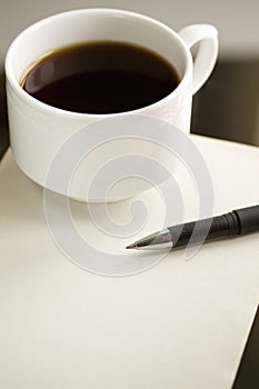 Cup of coffee and pen on the paper.