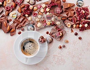 Cup of coffee with pieces of milk chocolate with nuts and chocolate candies