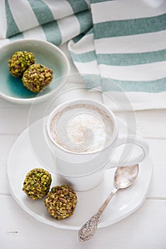 A cup of coffee and pistachio candies