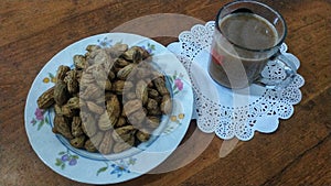 a cup of coffee and a plate of boiled peanuts