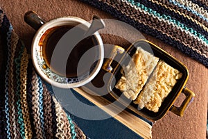 Cup of coffee, plate with cake, book and warm scarf