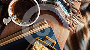 Cup of coffee, plate with cake, book and warm scarf