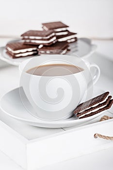 Cup of coffee and plate with cookies on a white tray