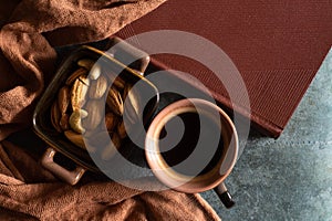 Cup of coffee, plate with nuts, book and warm scarf