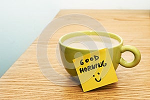 Cup of coffee, post-it note good morning and smiley