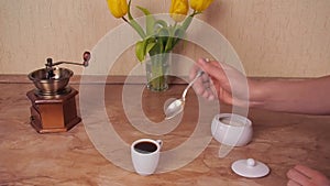 The cup of coffee poured sugar. The white cup of hot coffee with sugar added. Marble Table. White sugar bowl.