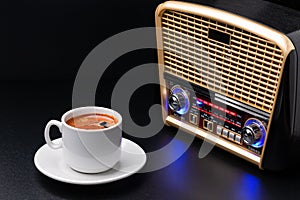 Cup of coffee and radio receiver on black background